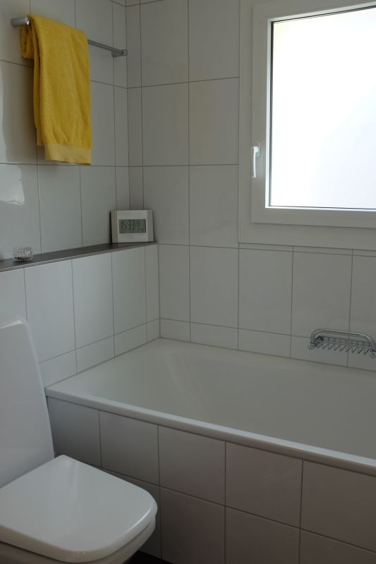 Helles Badezimmer mit Badewanne und Fenster