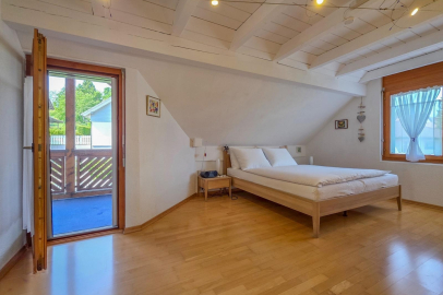 Helles Schlafzimmer mit Holzdecke und Balkonzugang