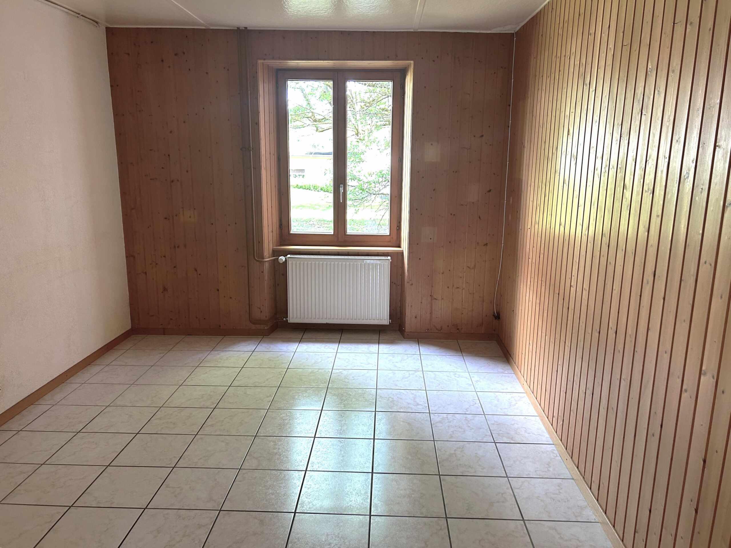 Leerer Raum mit Holzverkleidung und Fliesenboden