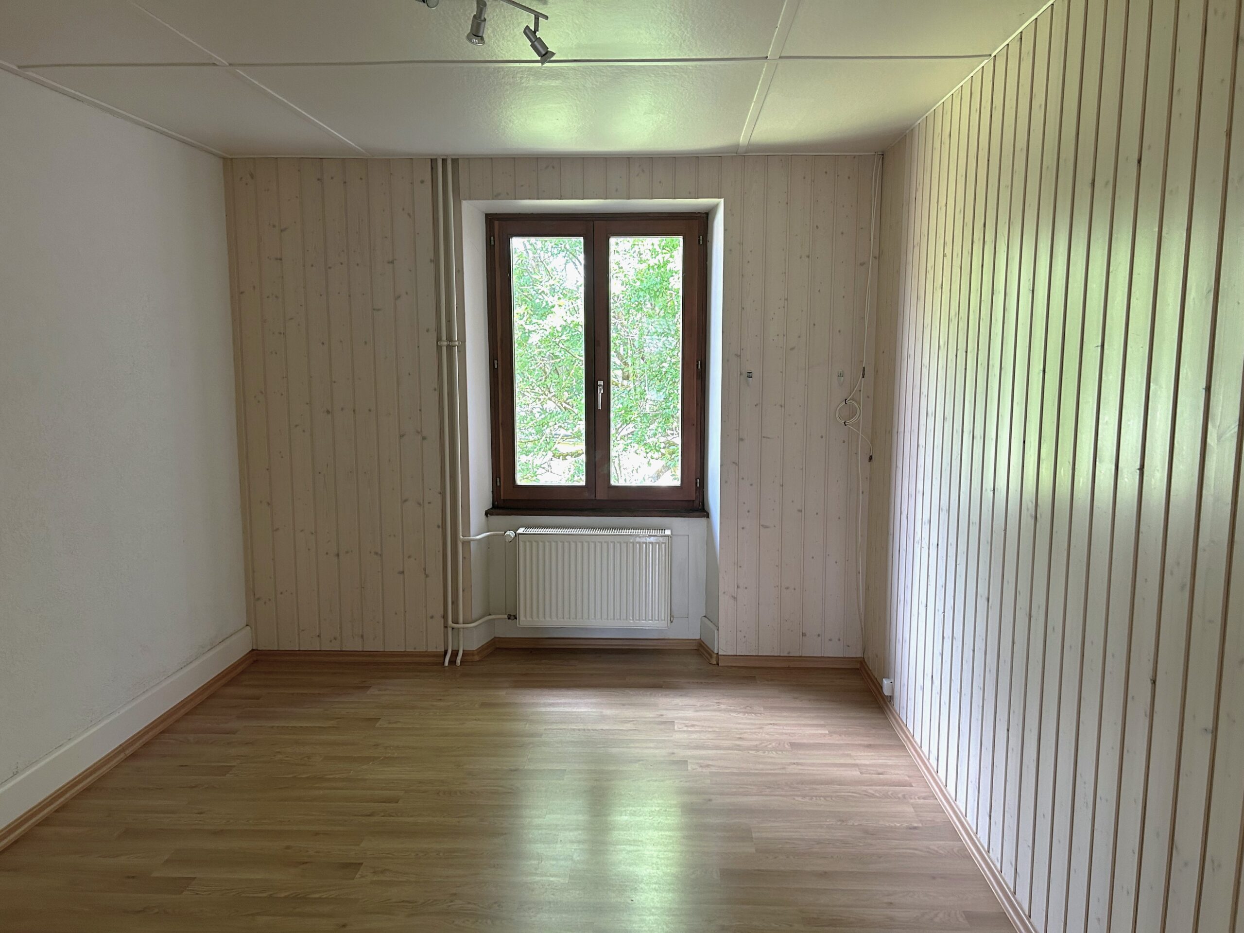 Leeres Zimmer mit Holzverkleidung und Fenster