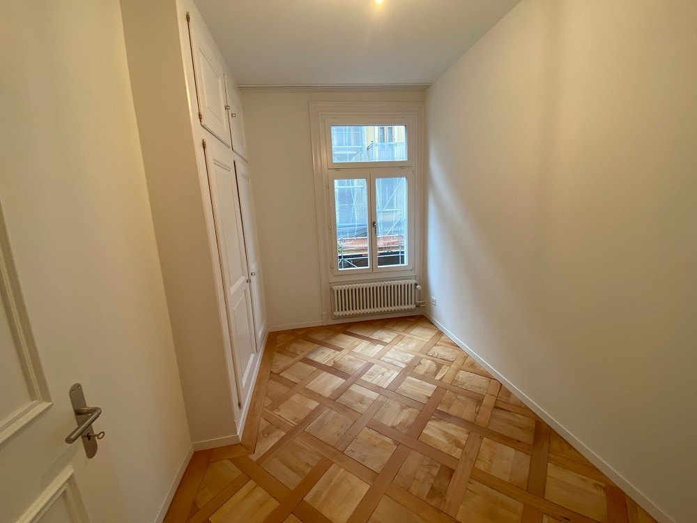 Heller, schmaler Flur mit Fischgrätparkett und Fenster