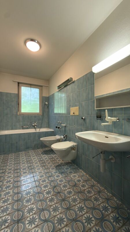Badezimmer mit blauen Fliesen und Musterboden