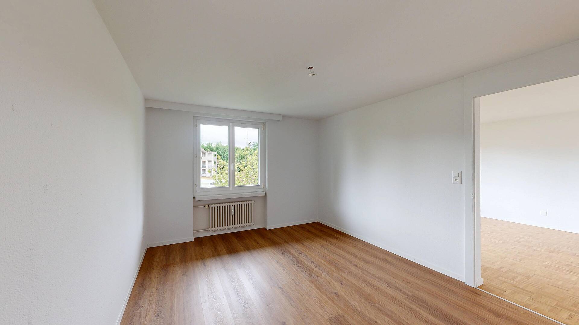 Heller leerer Wohnraum mit Holzoptik-Boden
