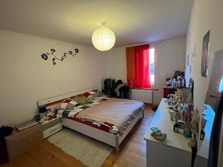 Schlafzimmer mit Doppelbett und rotem Vorhang