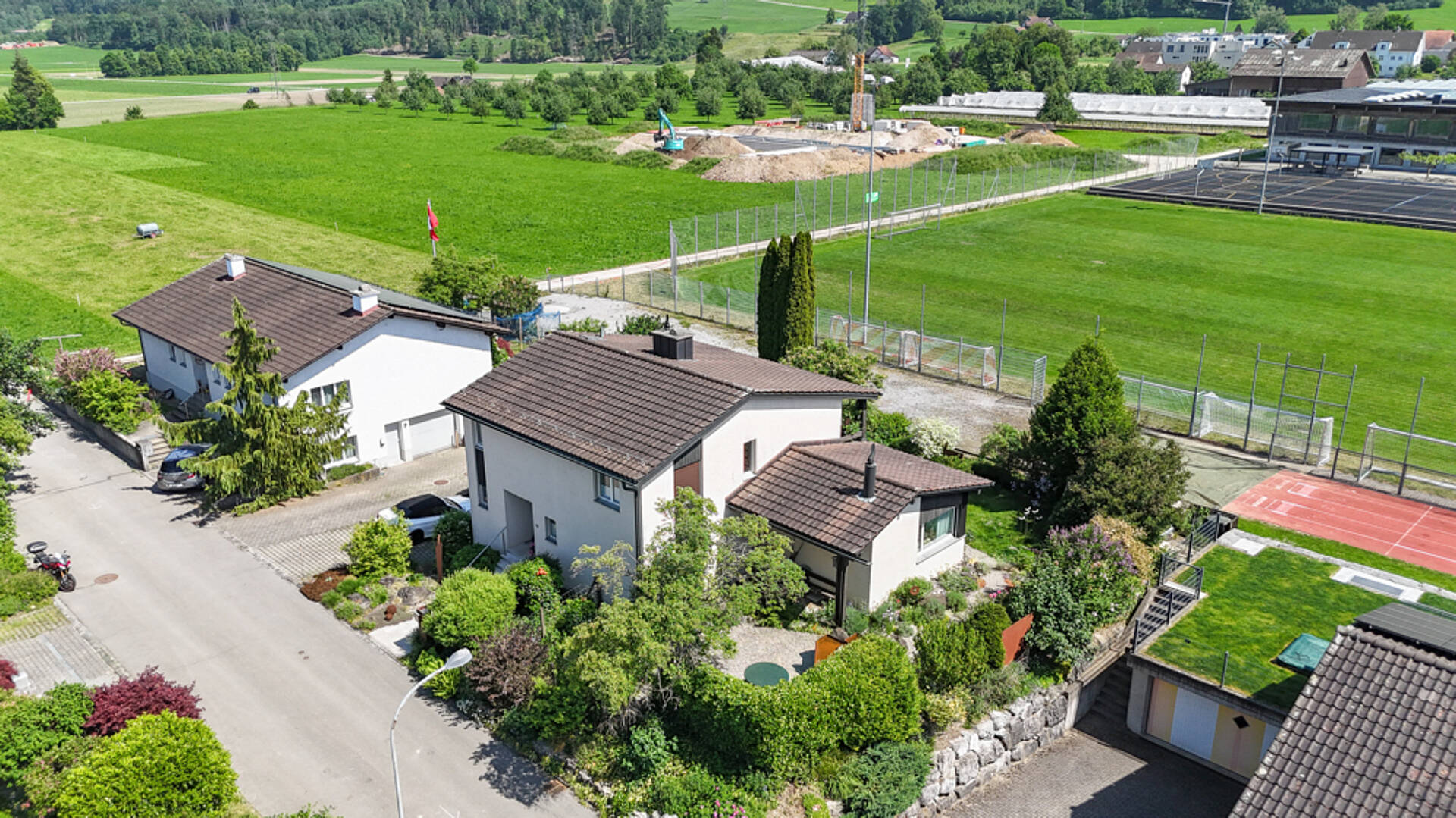 Luftaufnahme eines Wohnhauses mit Garten und Sportanlagen