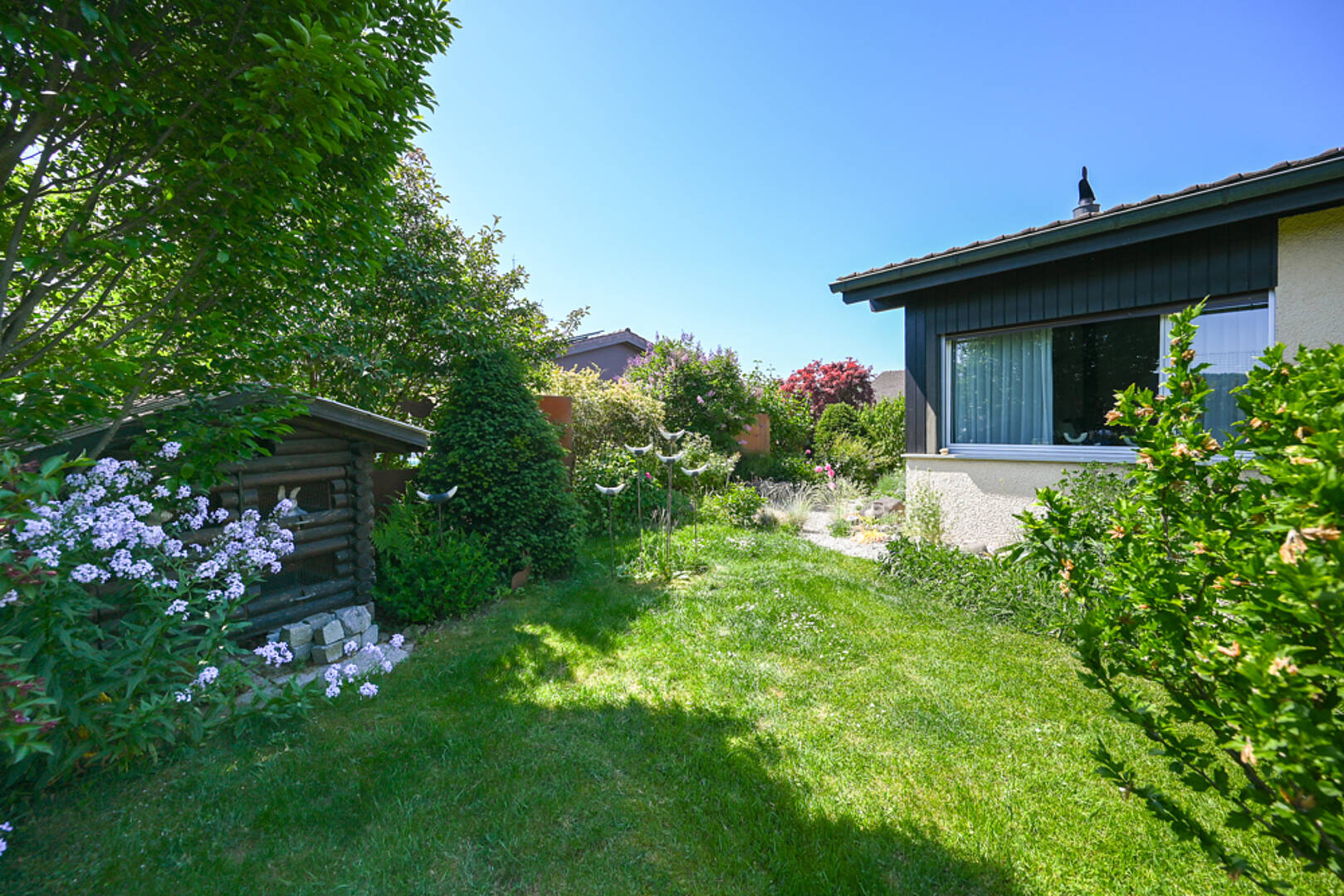 Garten mit gepflegtem Rasen und Hausansicht
