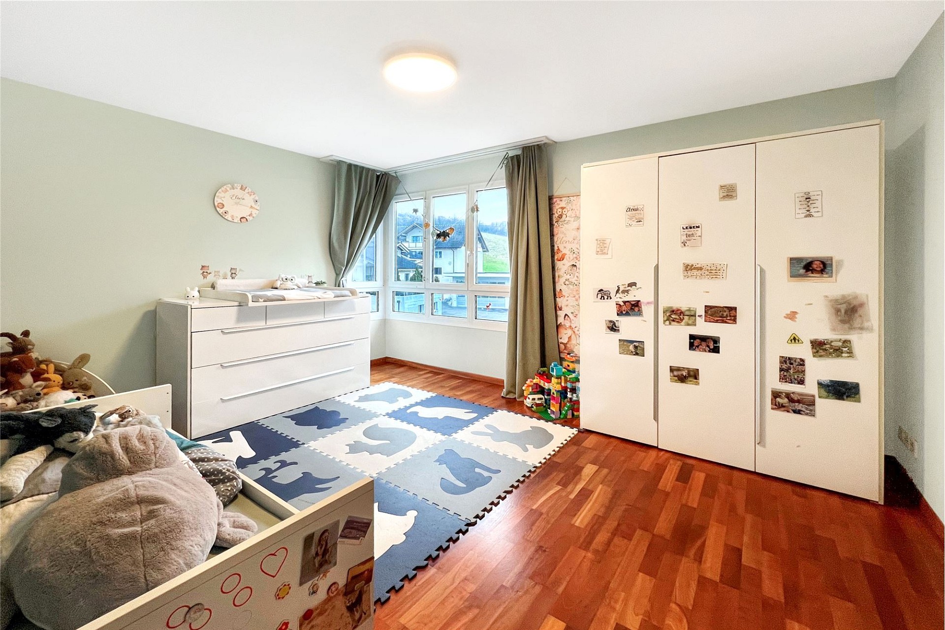 Helles Kinderzimmer mit Fensterfront und Kleiderschrank
