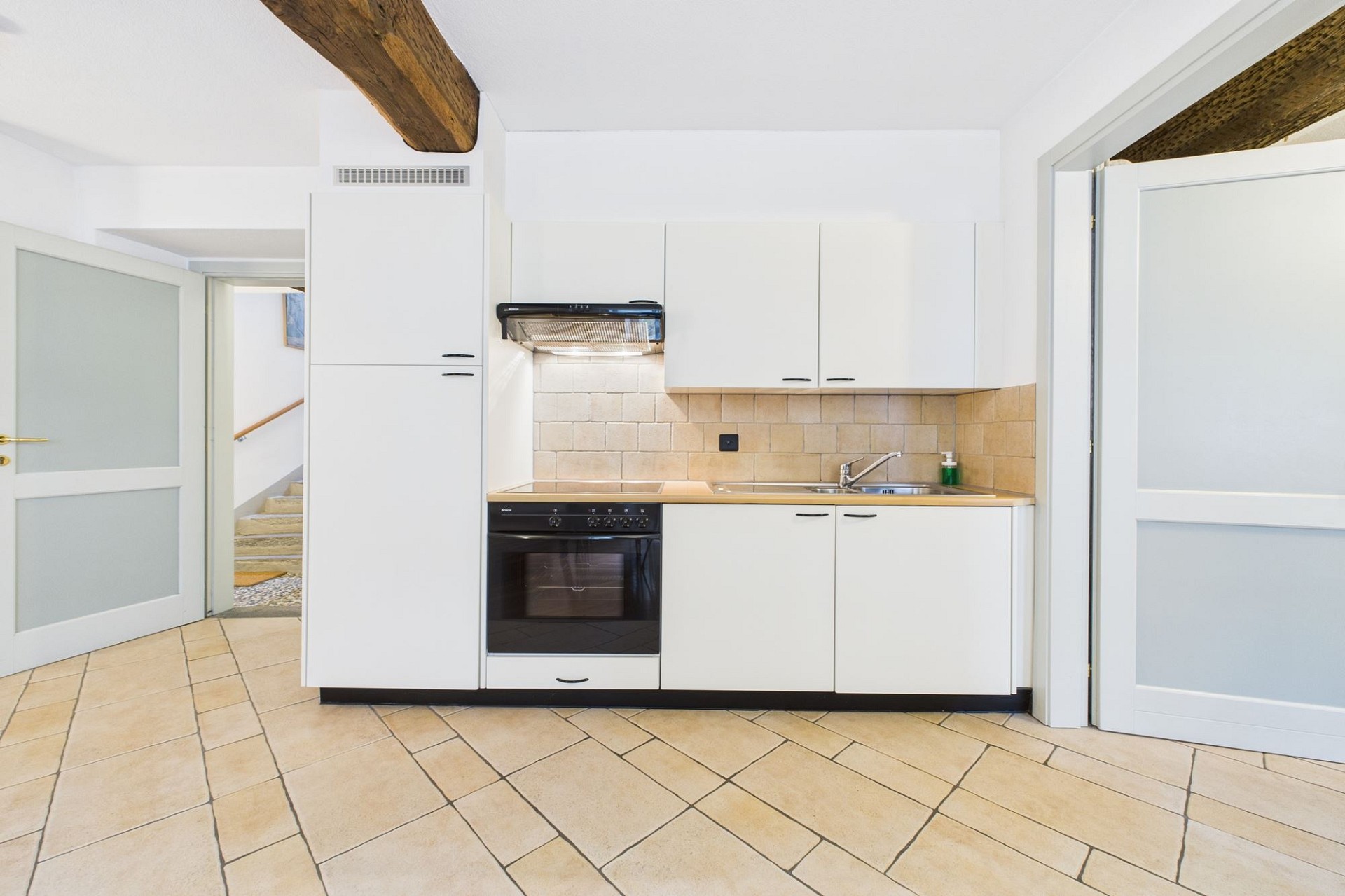 Helle Küche mit weißen Fronten und Natursteinboden