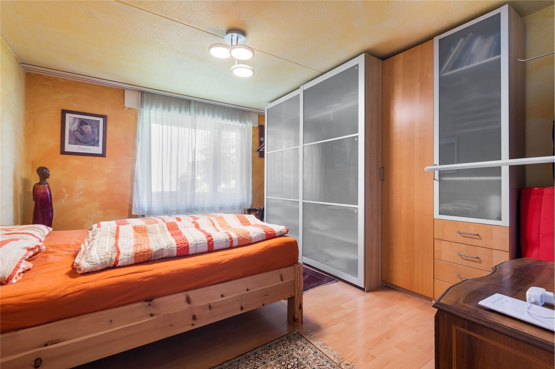 Schlafzimmer mit warmen Farbtönen und Stauraumwand