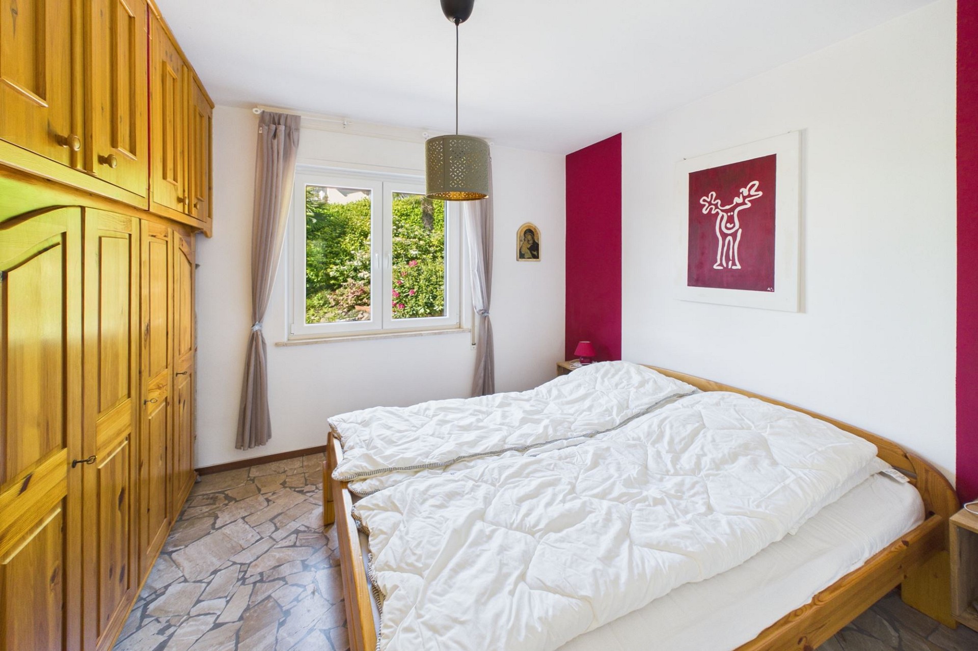 Helles Schlafzimmer mit Holzschrank und Gartenblick