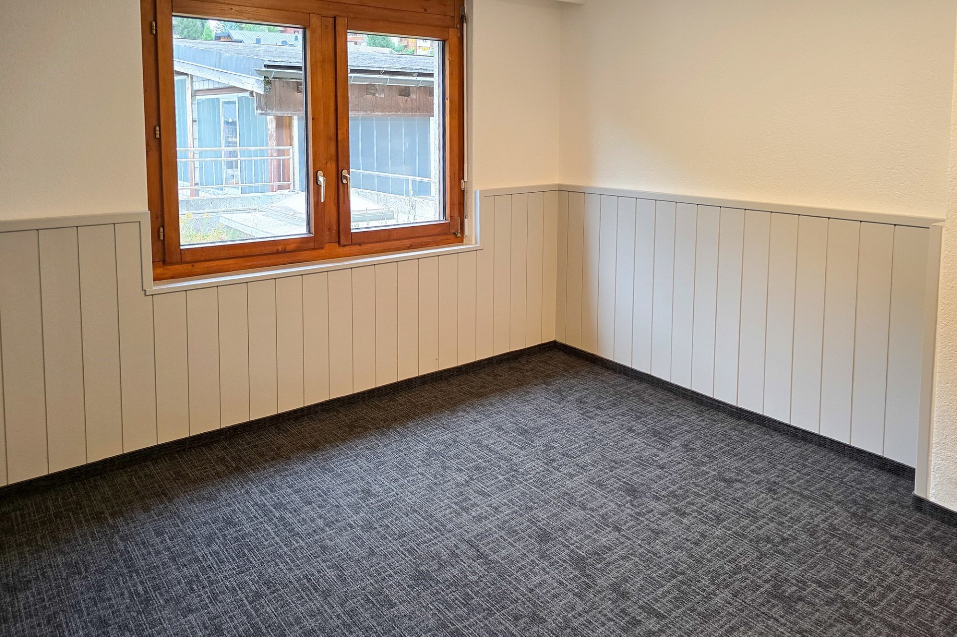 Leerer Raum mit Holzfenster und Teppichboden