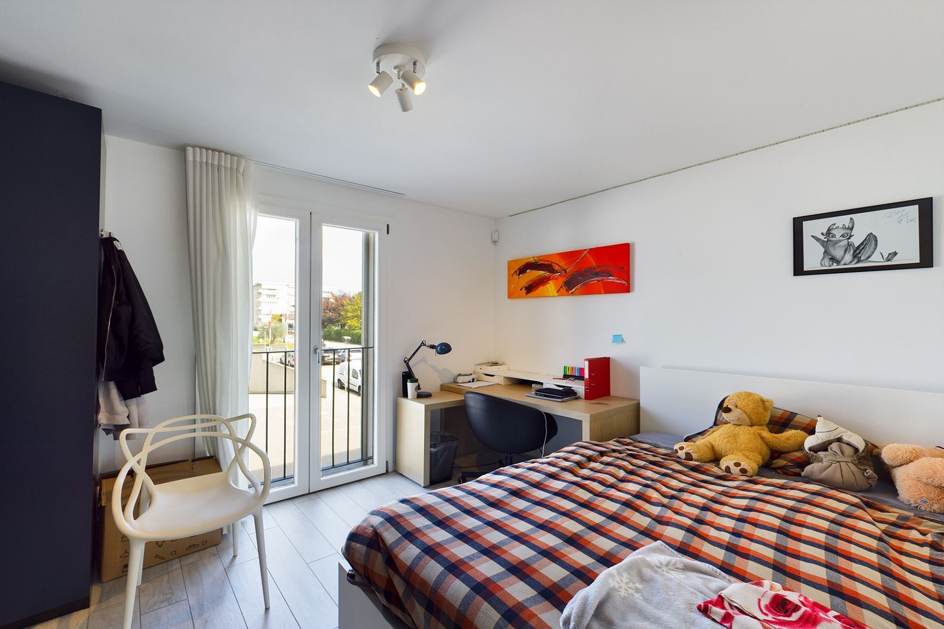 Helles Schlafzimmer mit Arbeitsbereich und Balkonzugang