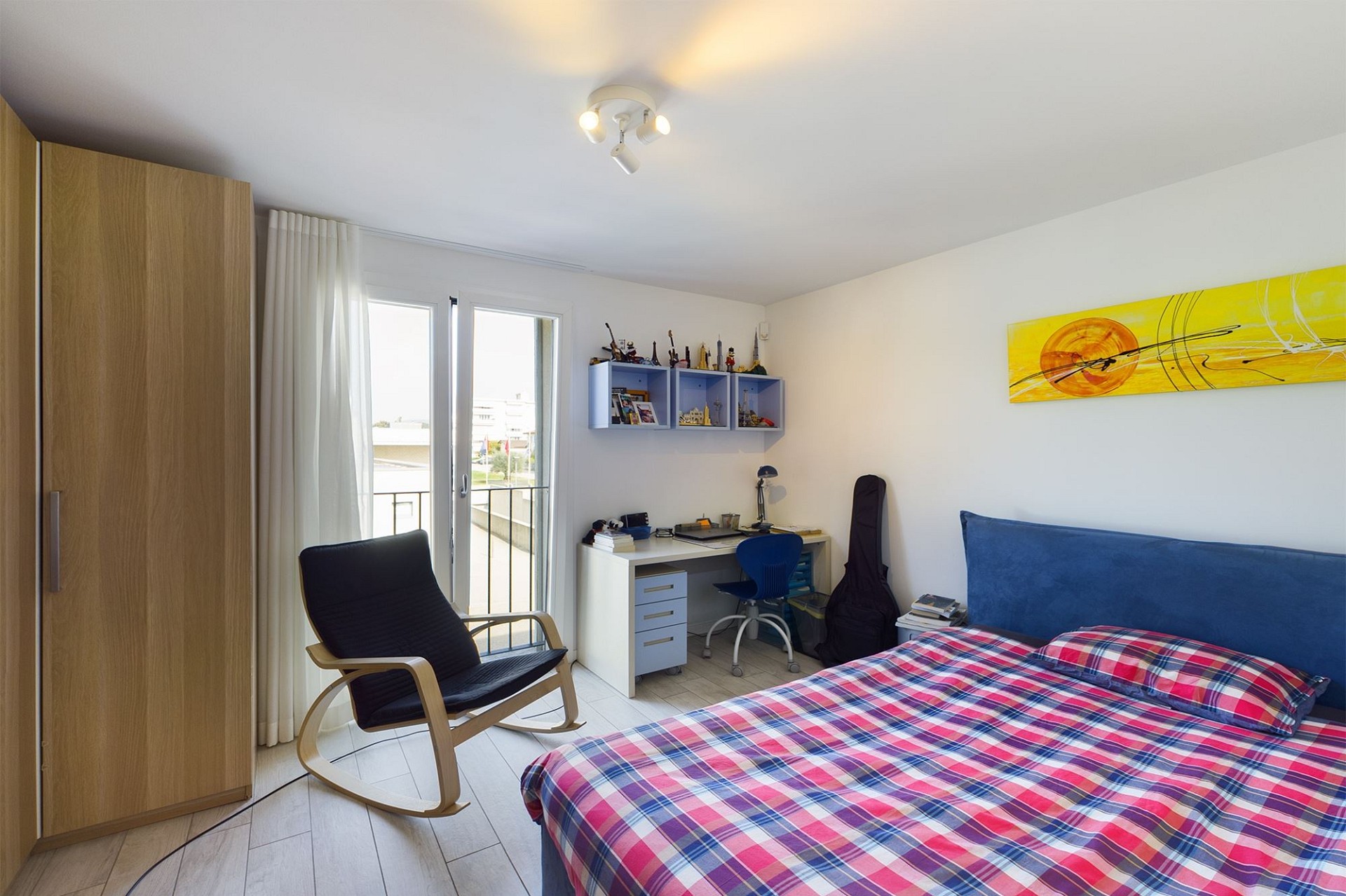 Helles Schlafzimmer mit Arbeitsplatz und Balkonzugang