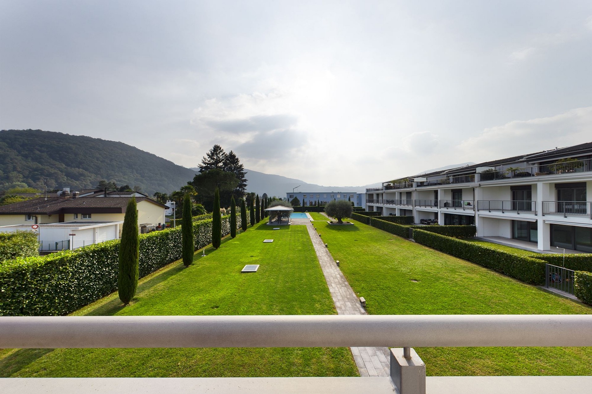 Außenansicht einer gepflegten Wohnanlage mit Garten und Bergblick