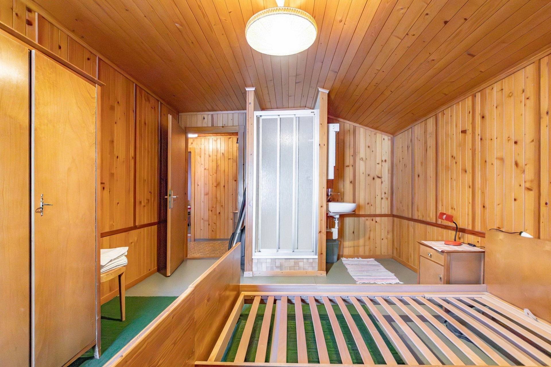 Dachzimmer mit Holzvertäfelung und kleiner Nasszelle