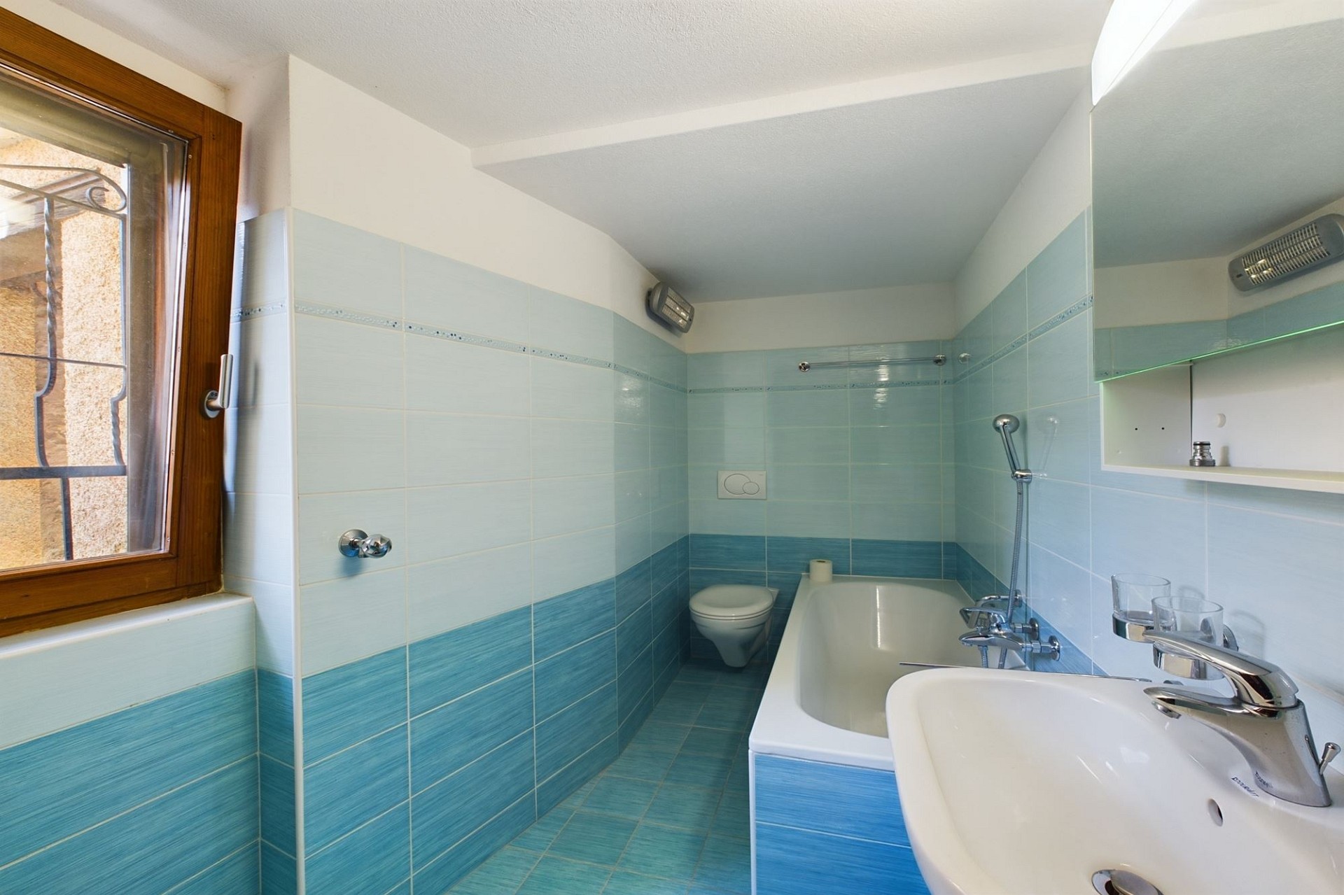 Kleines Badezimmer mit Badewanne und türkisfarbenen Fliesen