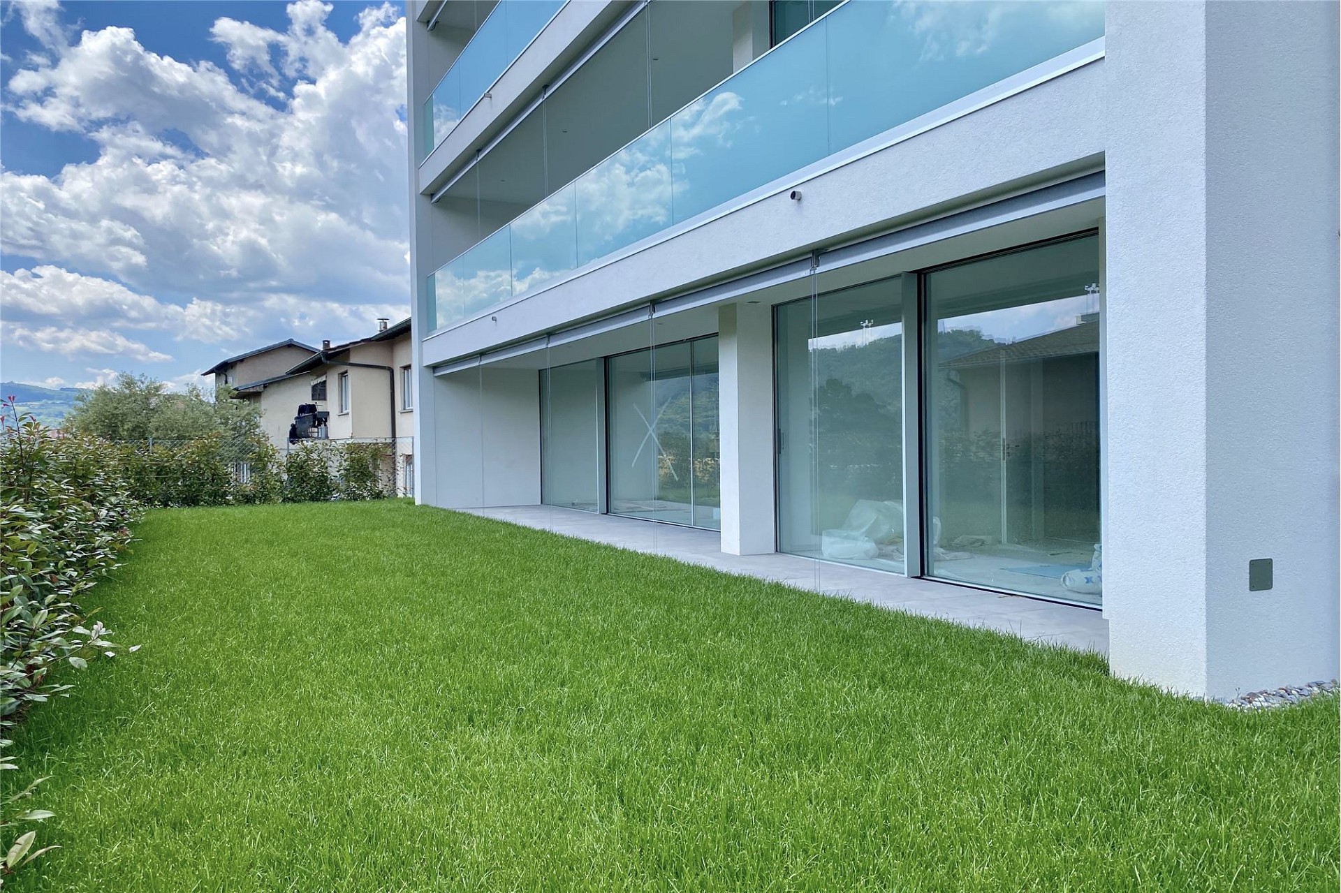 Moderne Wohnanlage mit Garten und Glasbalkonen