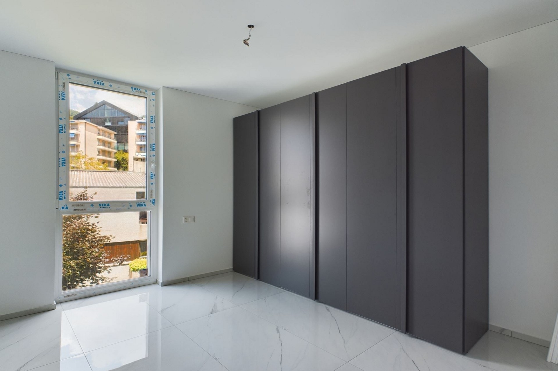 Heller, leerer Raum mit großem Fenster und Einbauschrank