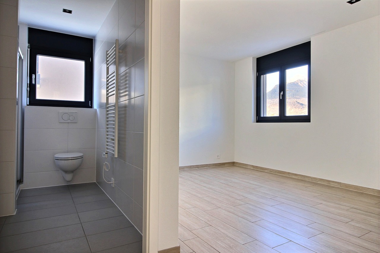 Modernes Badezimmer neben leerem Raum mit Bergblick