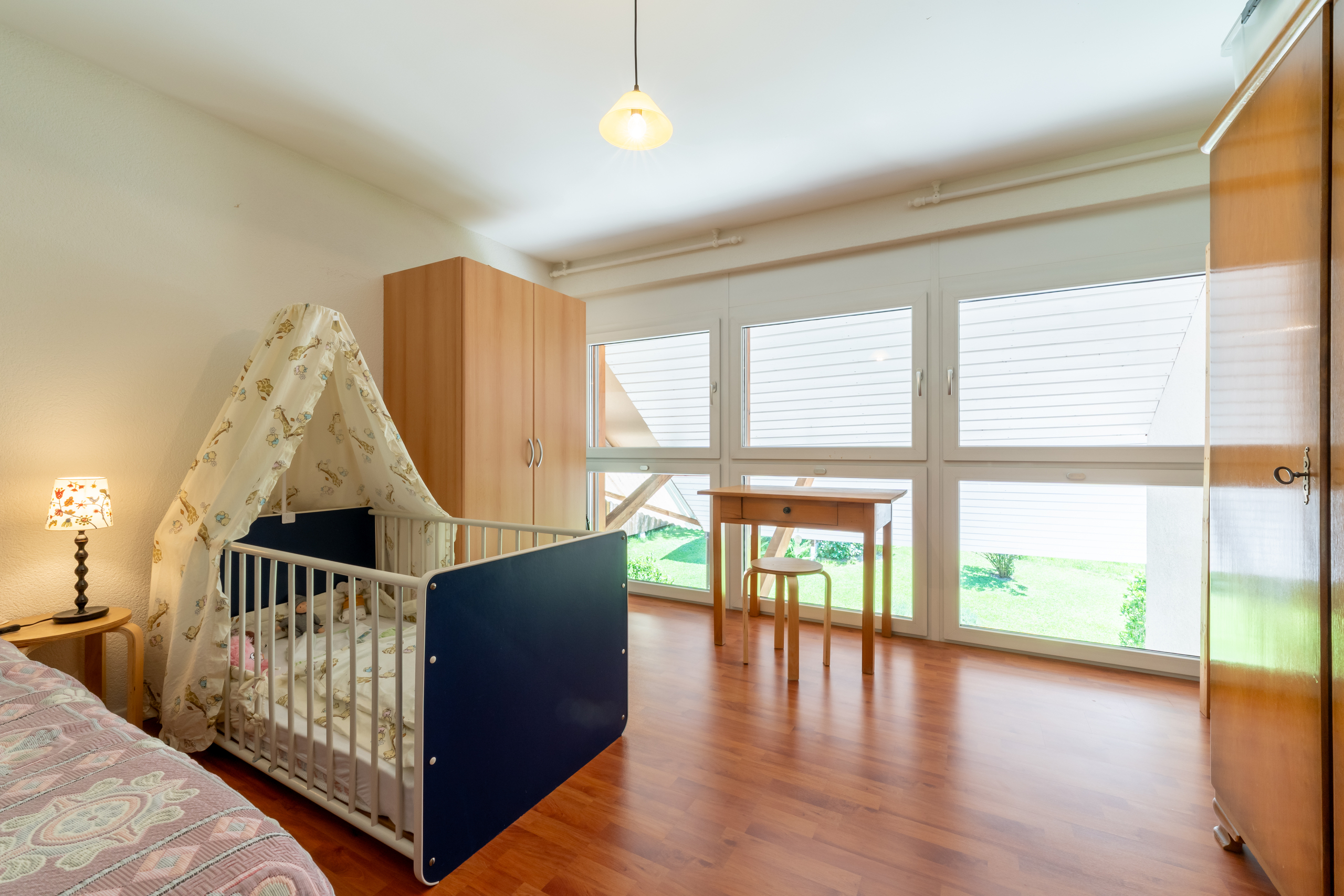 Helles Schlafzimmer mit Kinderbett und Schreibtisch