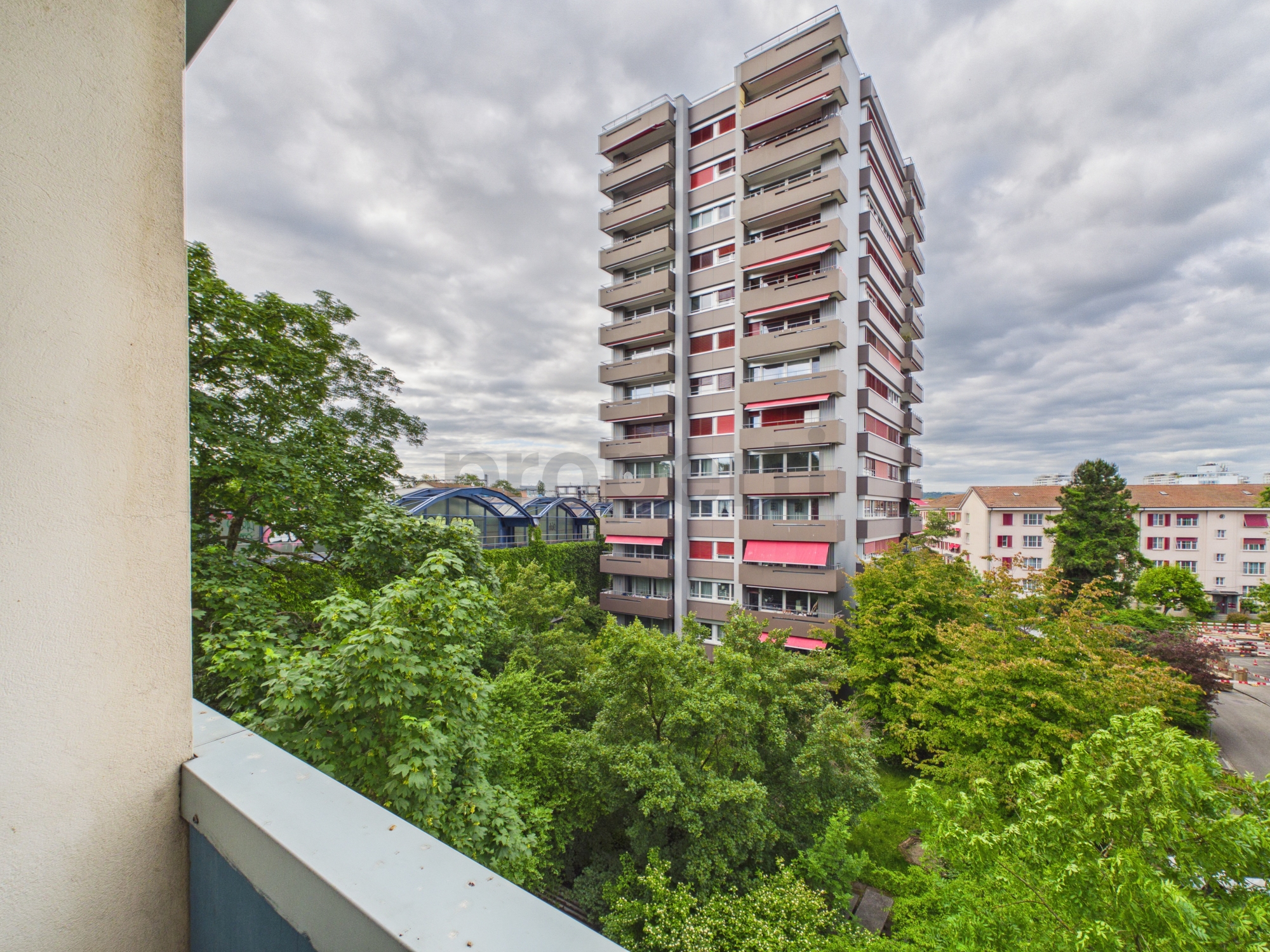 Blick vom Balkon auf ein Hochhaus und grüne Umgebung