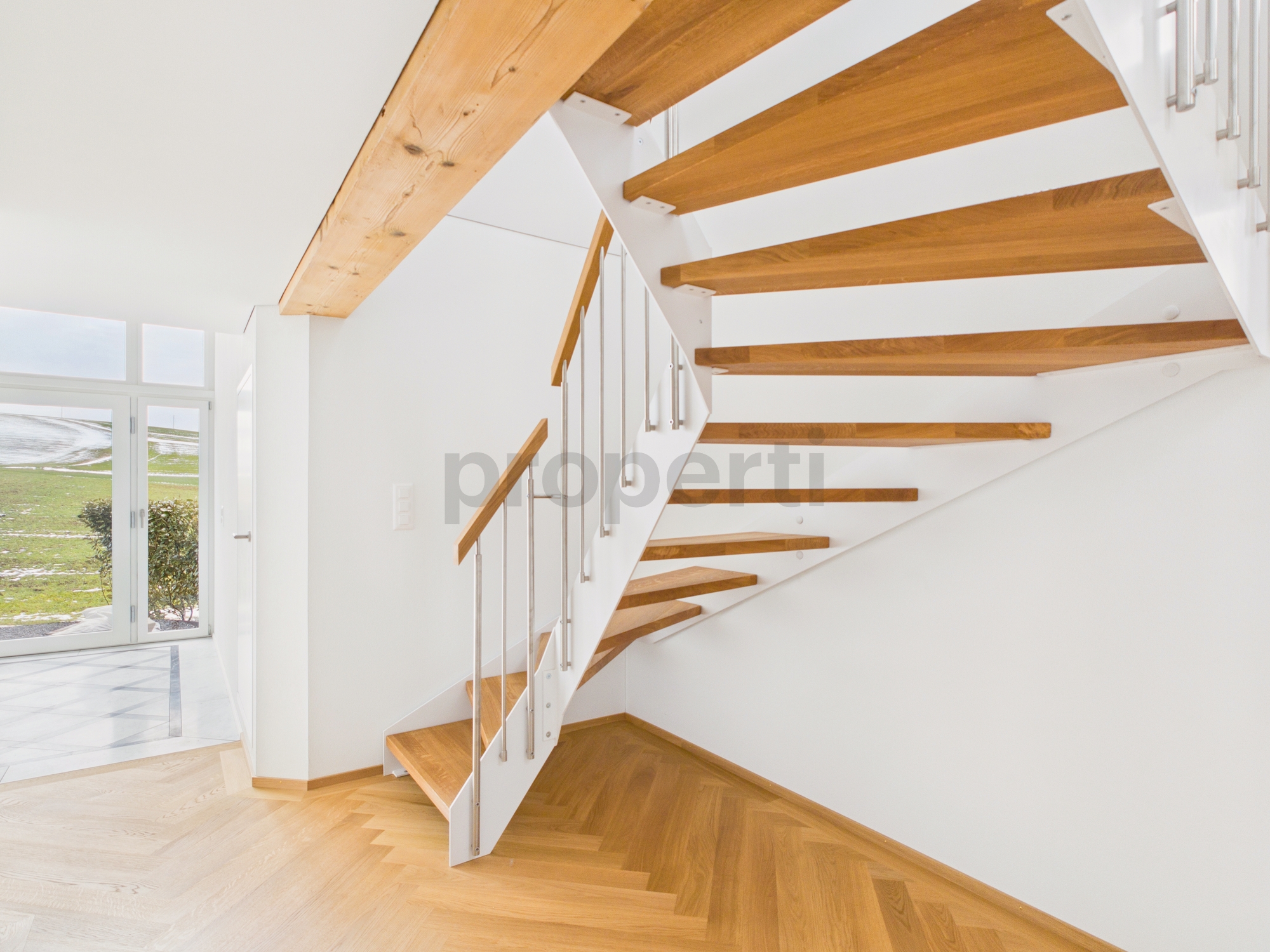 Heller Eingangsbereich mit freitragender Holztreppe
