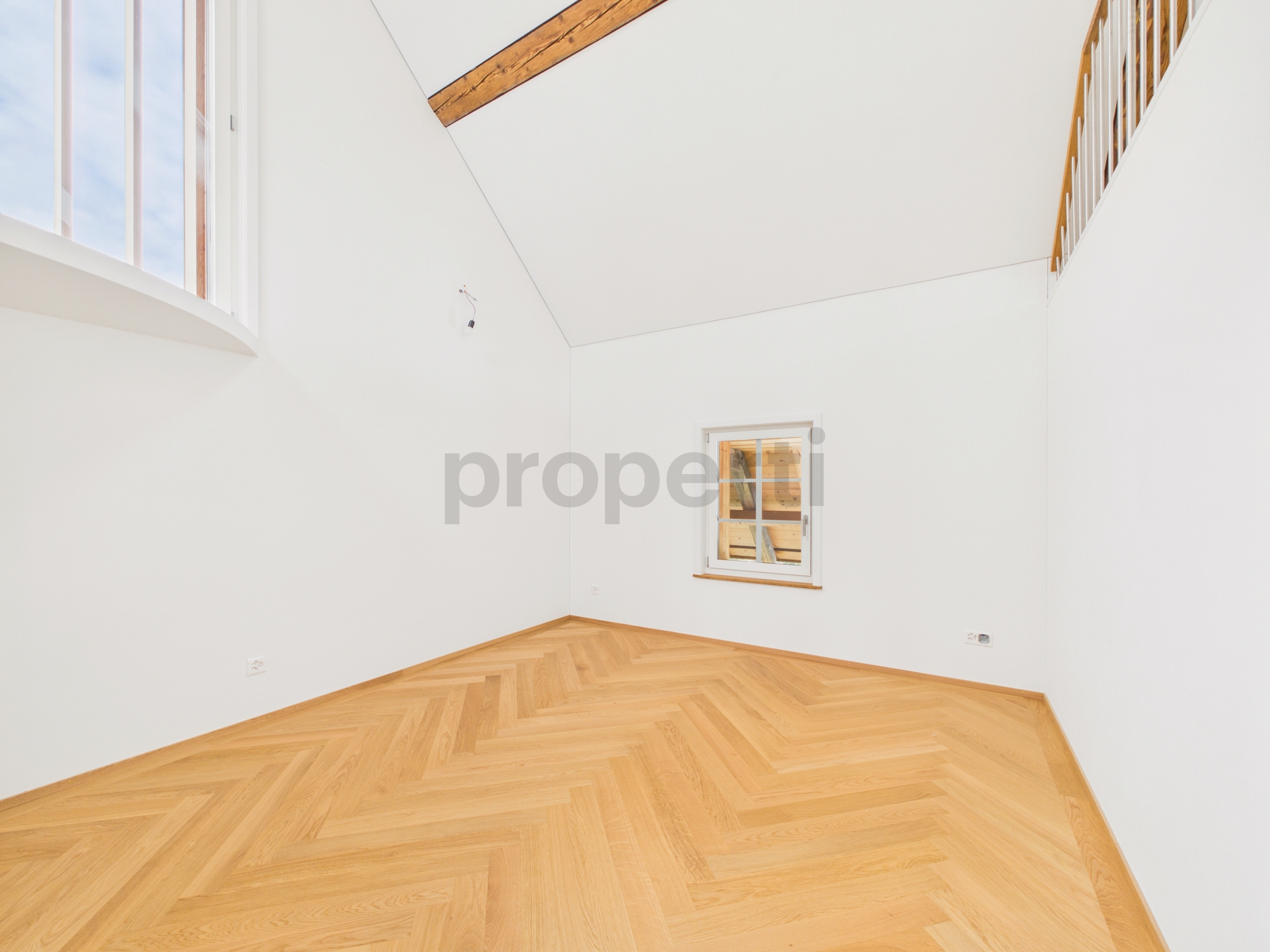 Heller leerer Raum mit hohen Decken und Holzfußboden