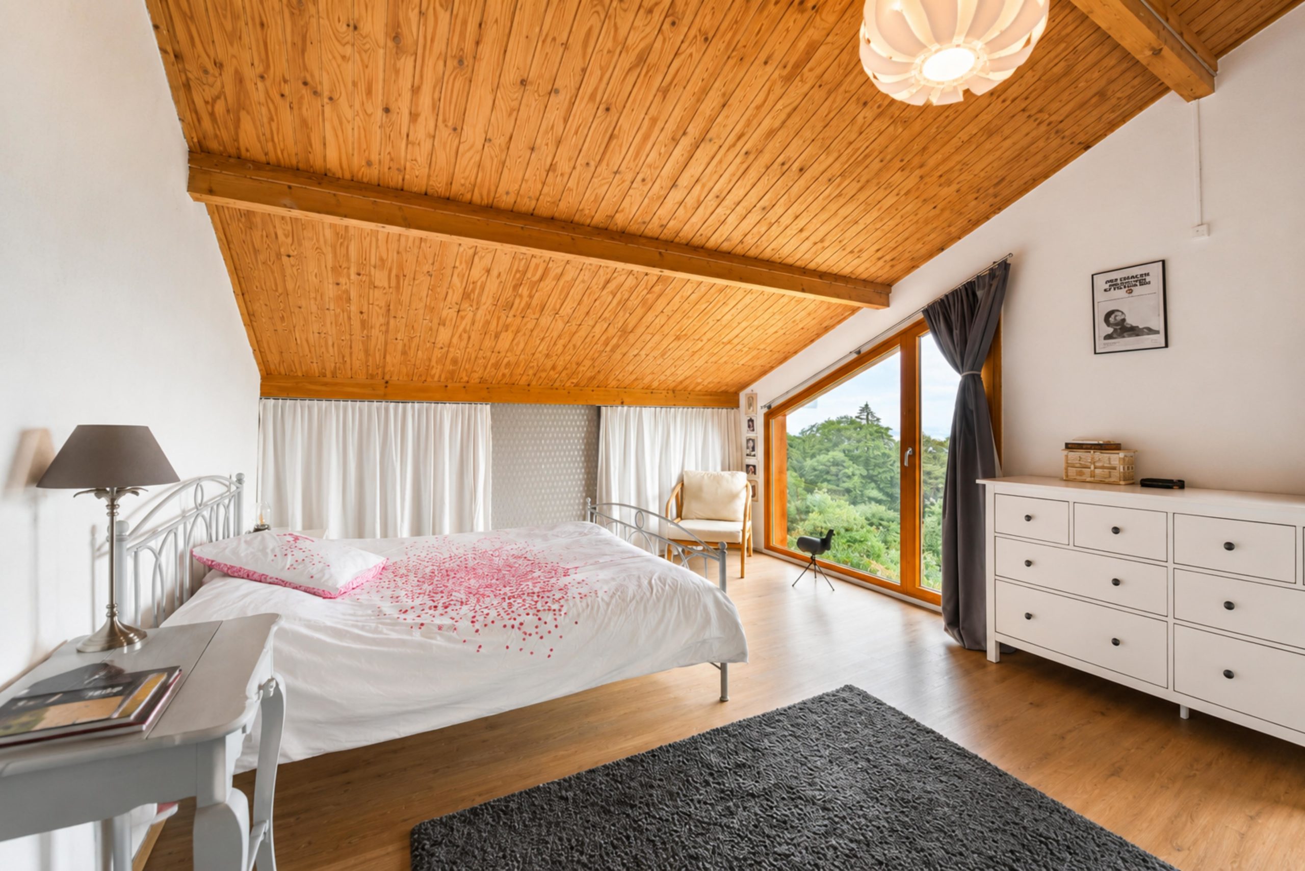 Helles Schlafzimmer mit Dachschräge und Blick ins Grüne