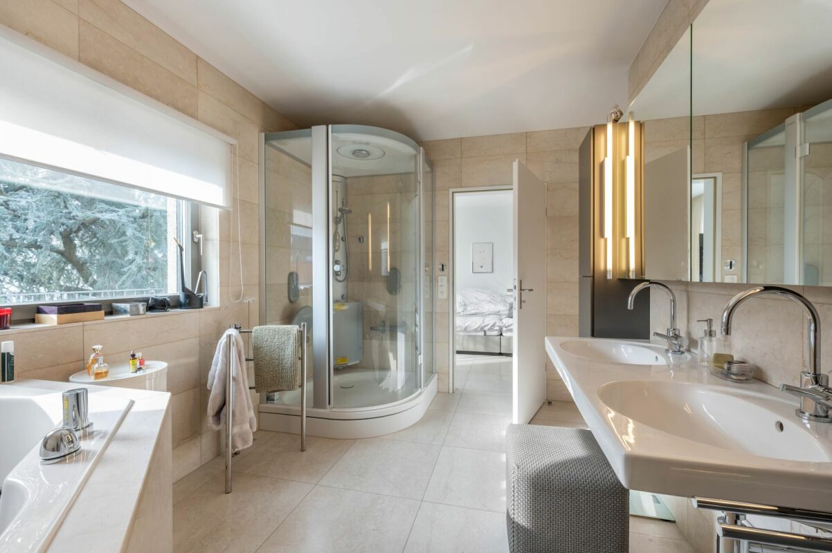 Modernes Badezimmer mit Doppelwaschbecken und runder Glasdusche