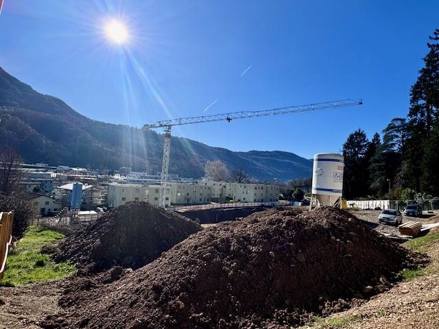 Baustelle in bergigem Tal unter sonnigem Himmel