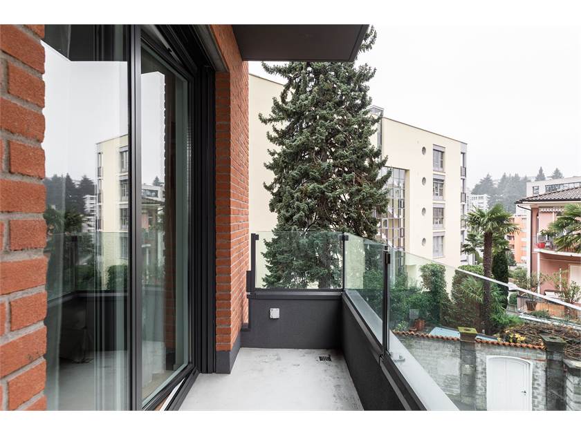Balkon mit Blick ins Grüne und auf Nachbargebäude