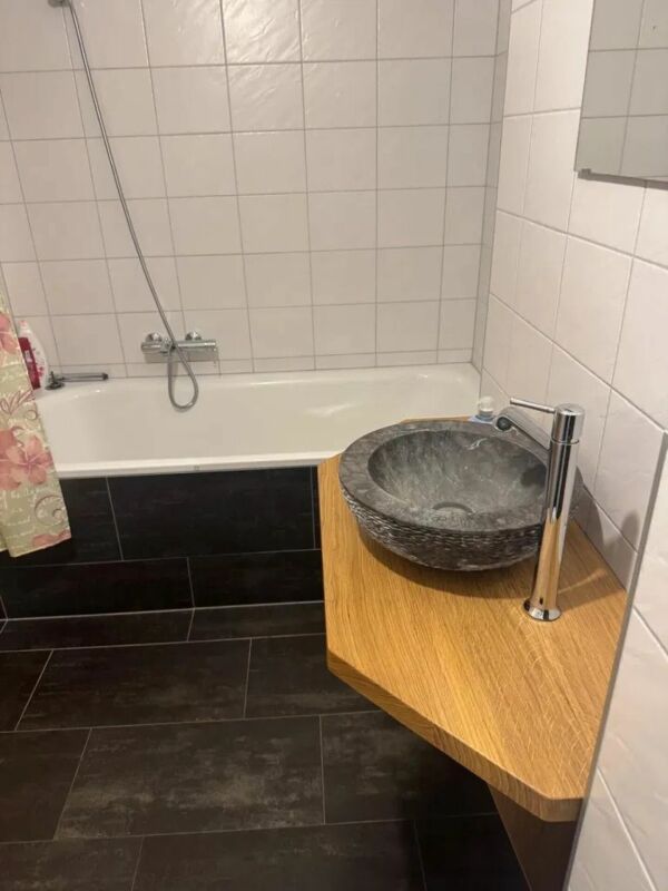 Badezimmer mit Wanne und Naturstein-Waschbecken