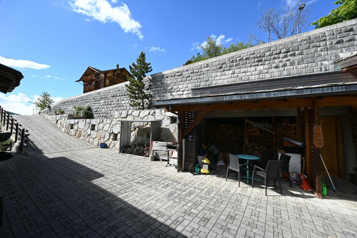 Terrasse mit Stützmauer und überdachtem Abstellbereich