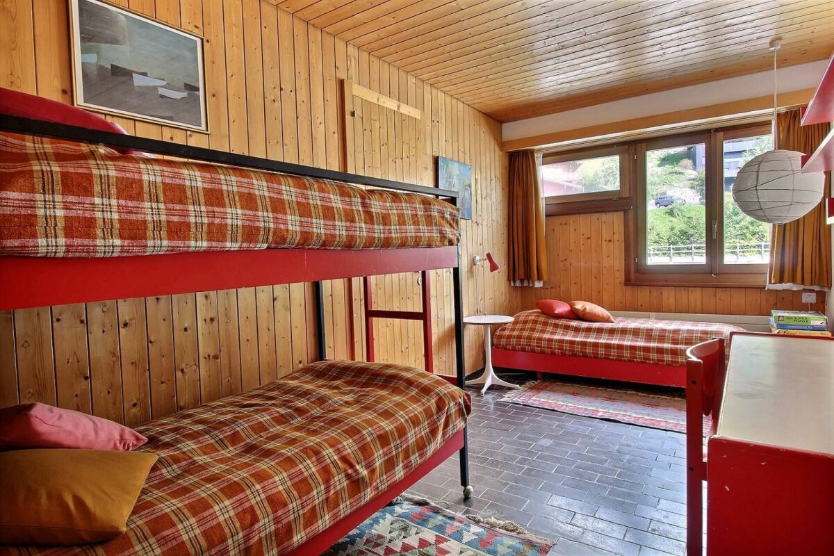 Holzverkleidetes Schlafzimmer mit Etagenbett und Einzelbett