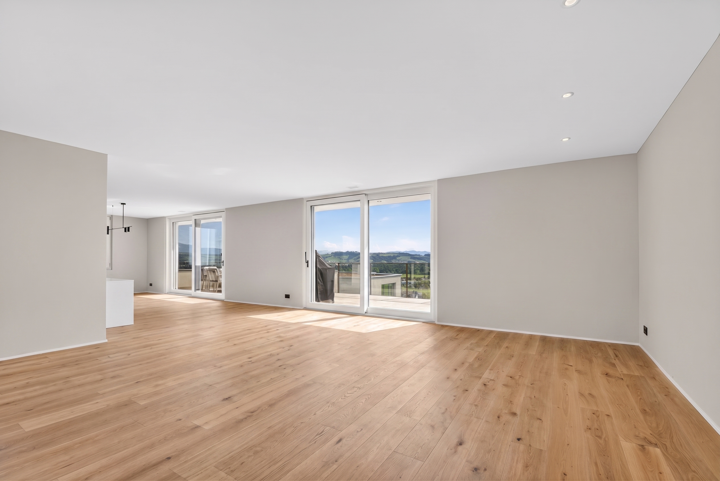 Heller leerer Wohnraum mit großen Fensterfronten und Ausblick