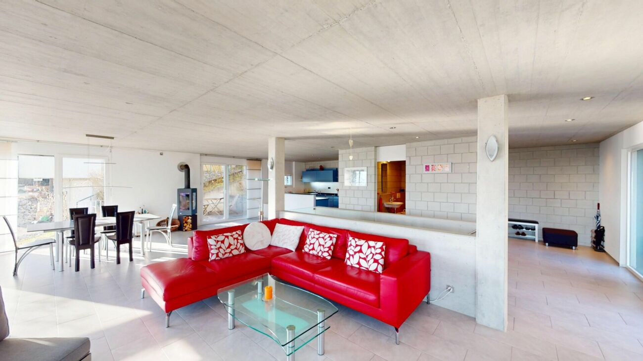 Offener Wohn-Ess-Bereich mit rotem Sofa und Kamin