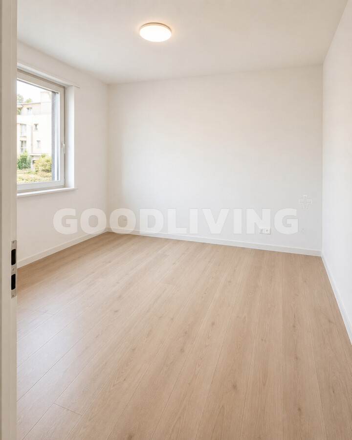 Helles, leeres Zimmer mit Parkett und Fenster