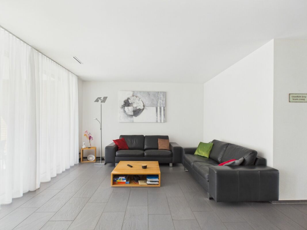 Heller moderner Wohnraum mit dunklen Sofas