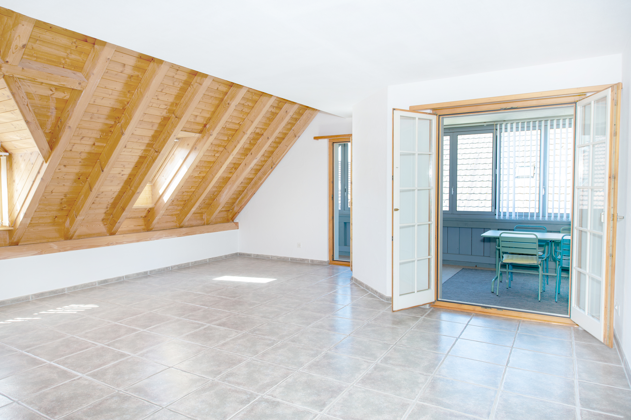 Heller Dachraum mit Holzbalken und Fliesenboden