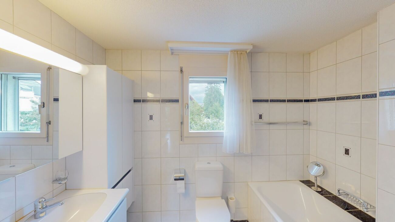 Helles Badezimmer mit Badewanne und Fenster