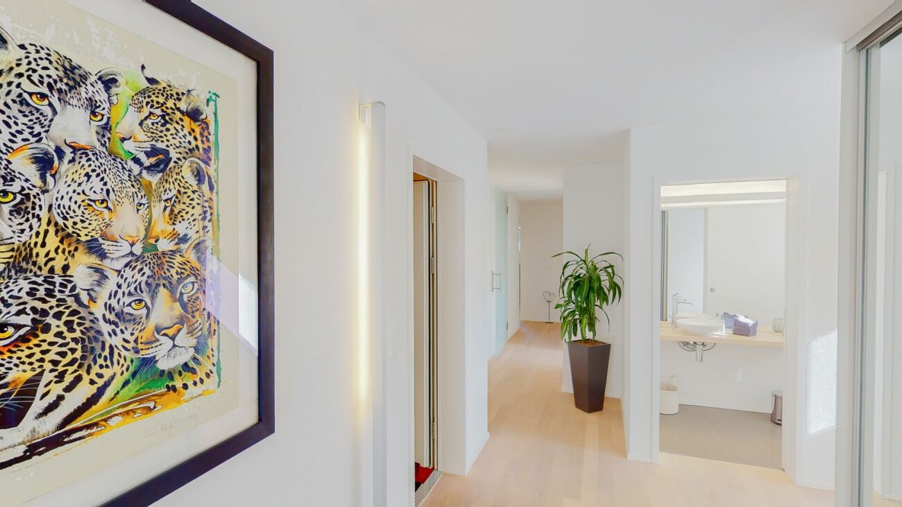 Heller Flur mit Kunstwerk und Blick ins Badezimmer