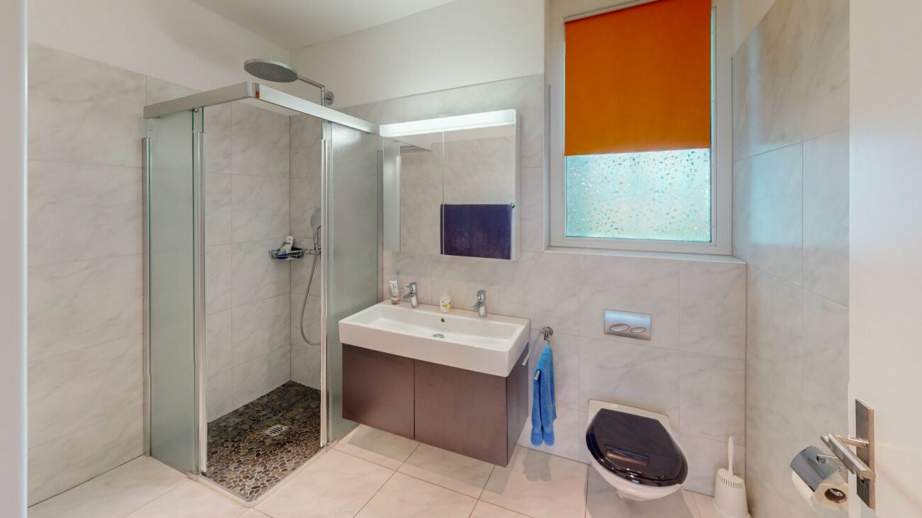 Modernes Badezimmer mit begehbarer Dusche und Fensterrollo