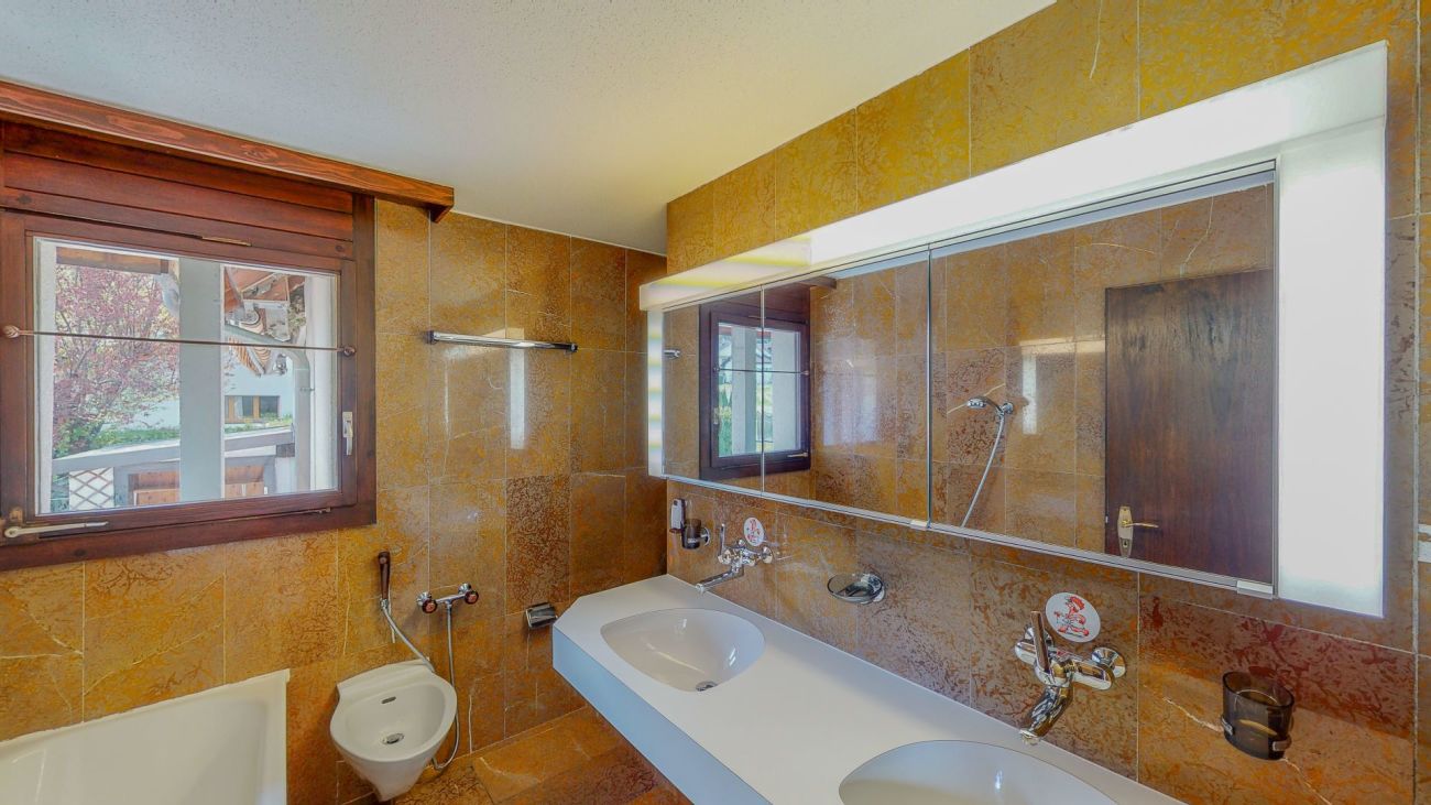 Badezimmer mit Holzfenster und Spiegelwand