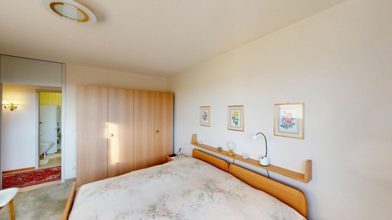 Helles Schlafzimmer mit Kleiderschrank und Blick ins angrenzende Bad