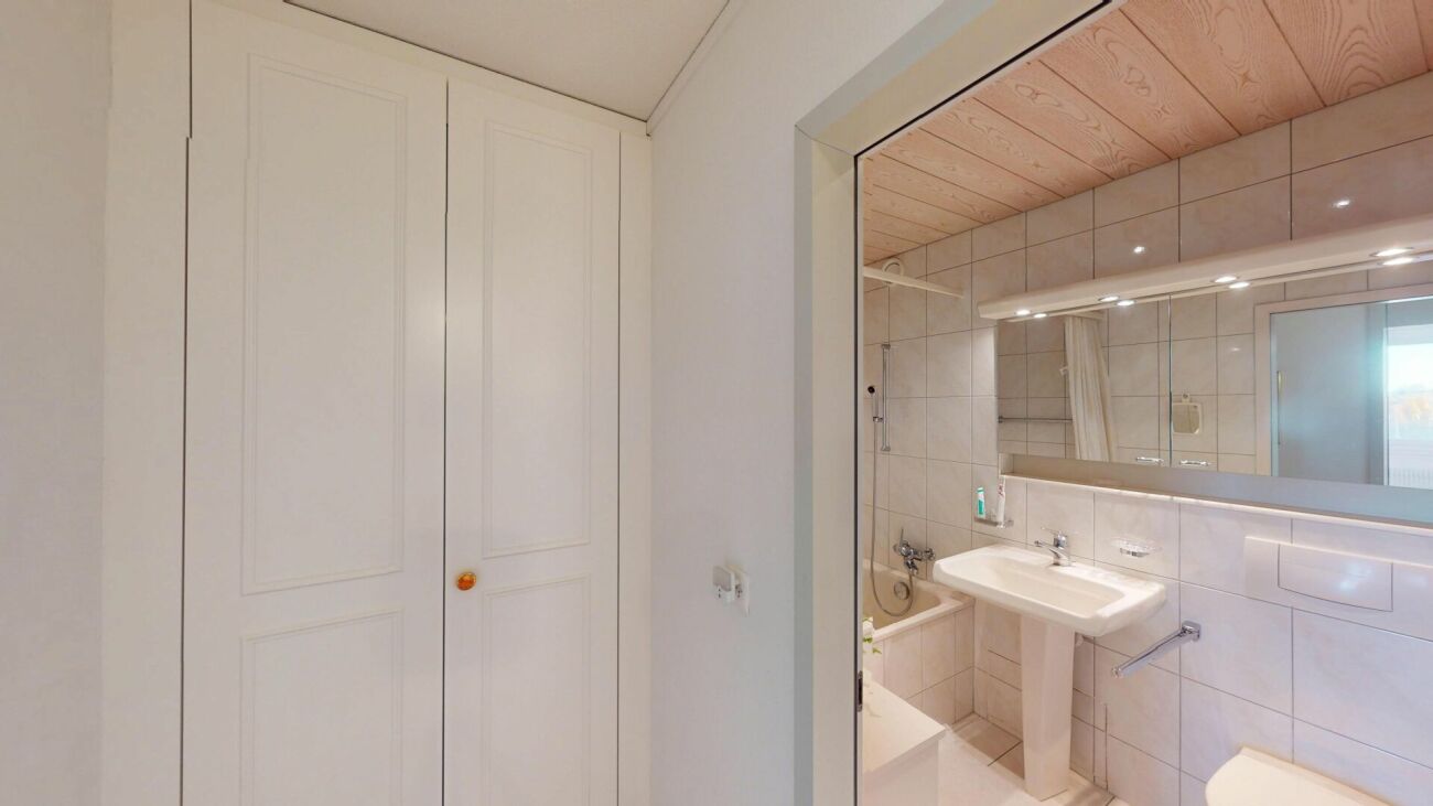 Hell gefliestes Badezimmer mit Blick in den Waschtischbereich