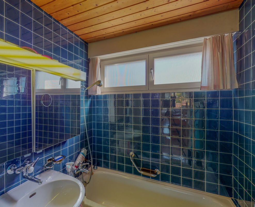 Badezimmer mit blauen Fliesen und Holzdecke
