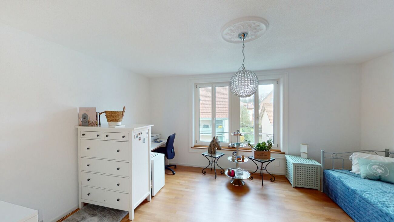 Helles Schlafzimmer mit Dachfenster-ähnlichem Fenster, Bett und kleinem Arbeitsbereich