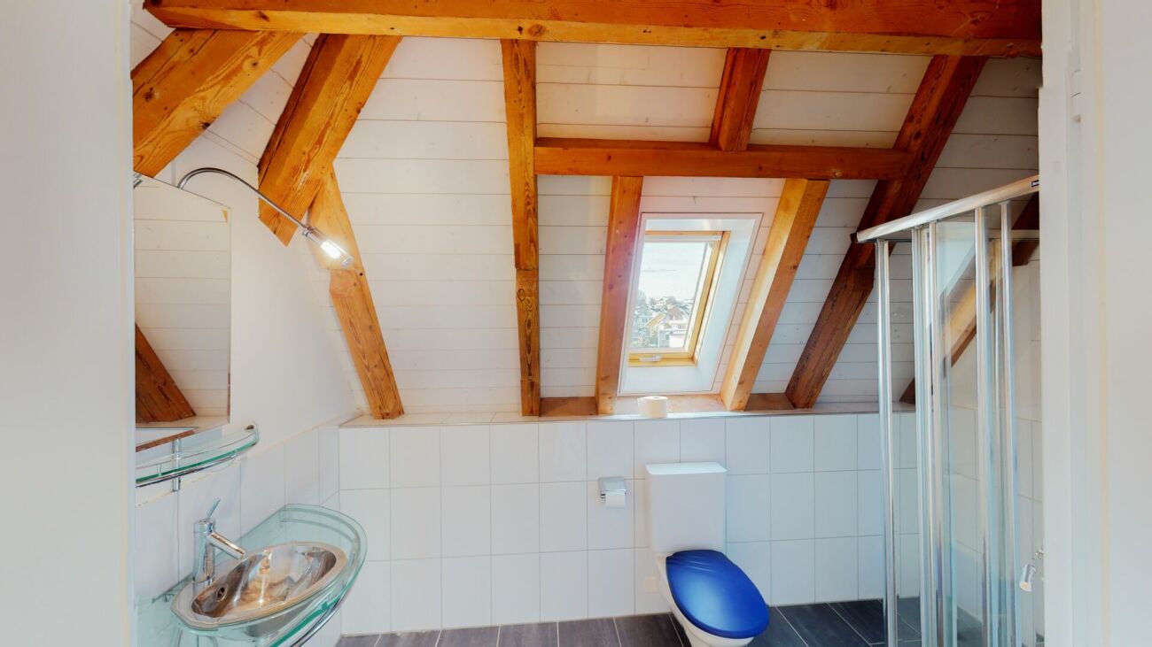 Dachgeschoss-Badezimmer mit sichtbaren Holzbalken