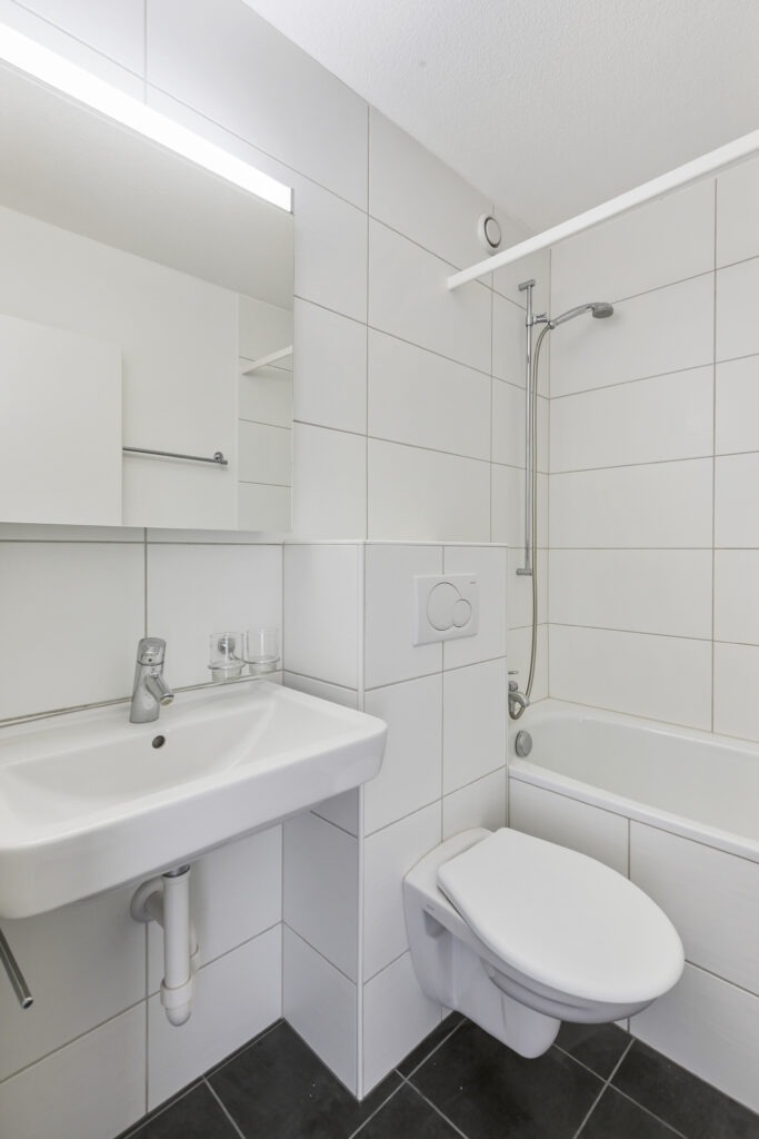 Kleines, helles Badezimmer mit Badewanne und wandhängendem WC