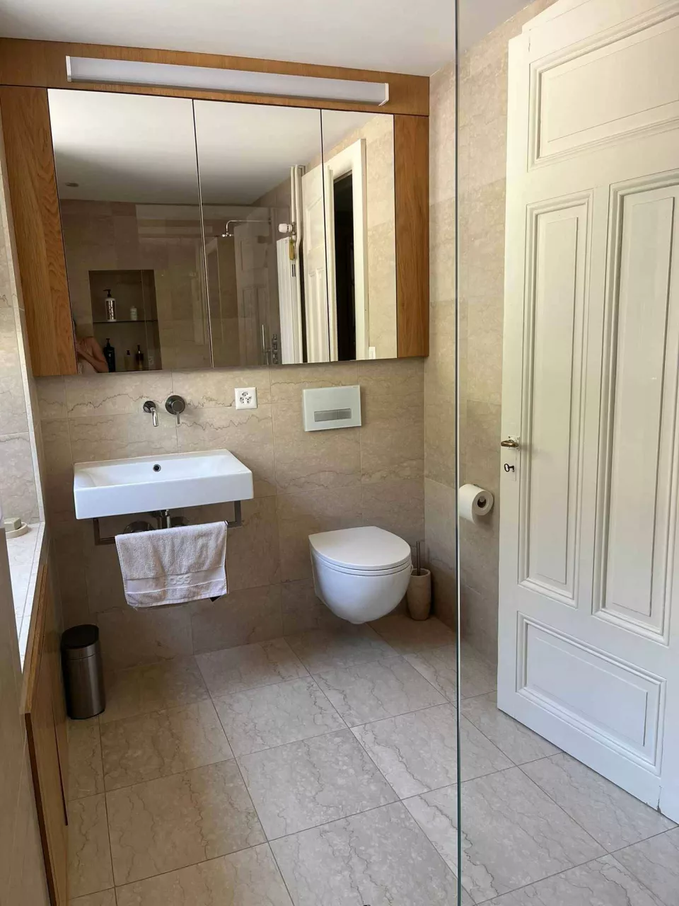 Helles Badezimmer mit Wand-WC und Holzspiegelschrank